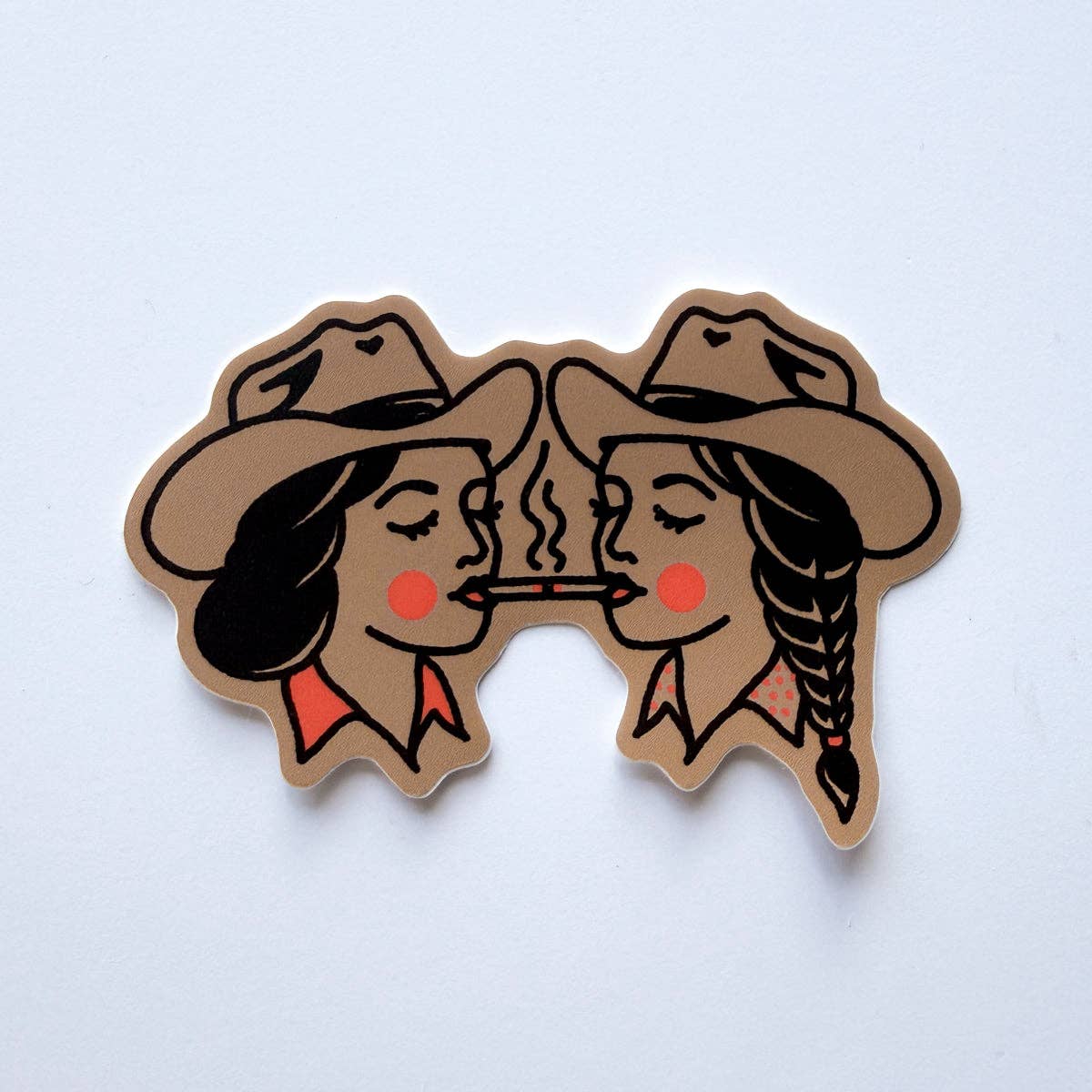 A die-cut sticker featuring a retro-style illustration of two women in cowboy hats facing each other with a cigarette between their lips, shown on a plain light background.