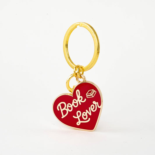Gold keychain with a red heart-shaped tag that says 'Book Lover' on a white background