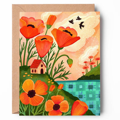 A square greeting card with a kraft envelope, featuring a colorful folk-art illustration of orange poppies, a small house, birds, and a blue-green landscape against a cream sky.