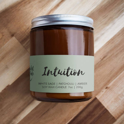 Candle jar labeled 'Intuition' on a wooden surface