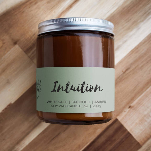 Candle jar labeled 'Intuition' on a wooden surface