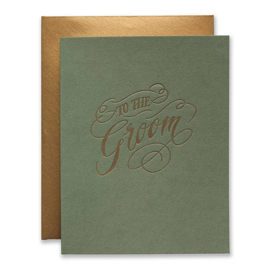 An olive green wedding card with 'To the Groom' written in elegant metallic rose-gold cursive, shown with a matching metallic gold envelope behind it on a white background.