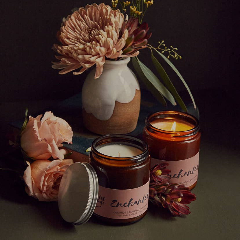 Two candles with floral arrangements on a dark background